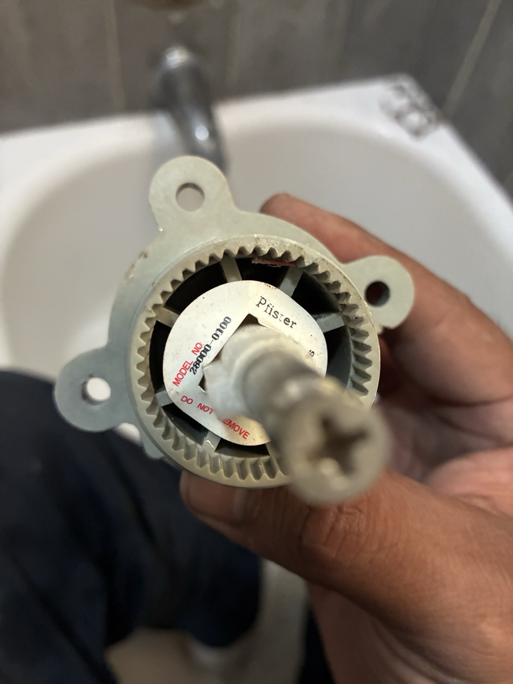 Technician holding a shower valve cartridge removed from the wall