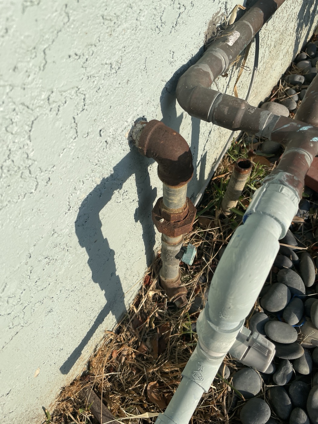 Exterior copper supply lines and backflow assembly on a stucco wall